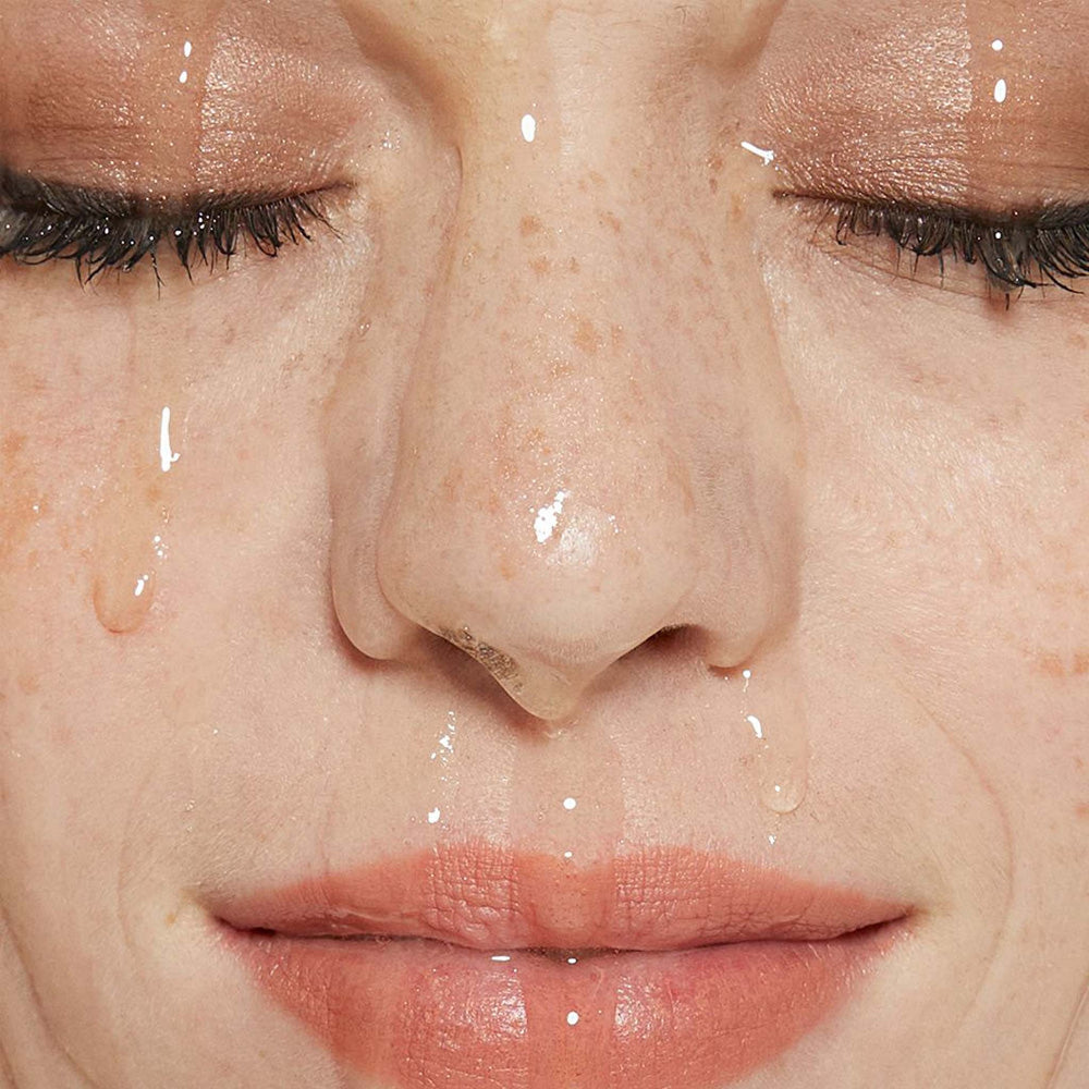Close-up of a person's face with dermalogica oil to foam total cleanser streaming down.