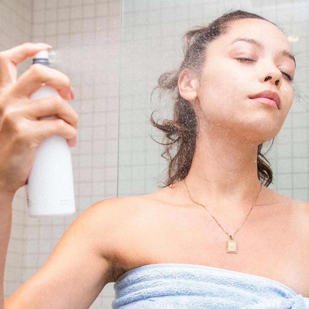 Woman next to a shower with a dermalogica multi-active toner