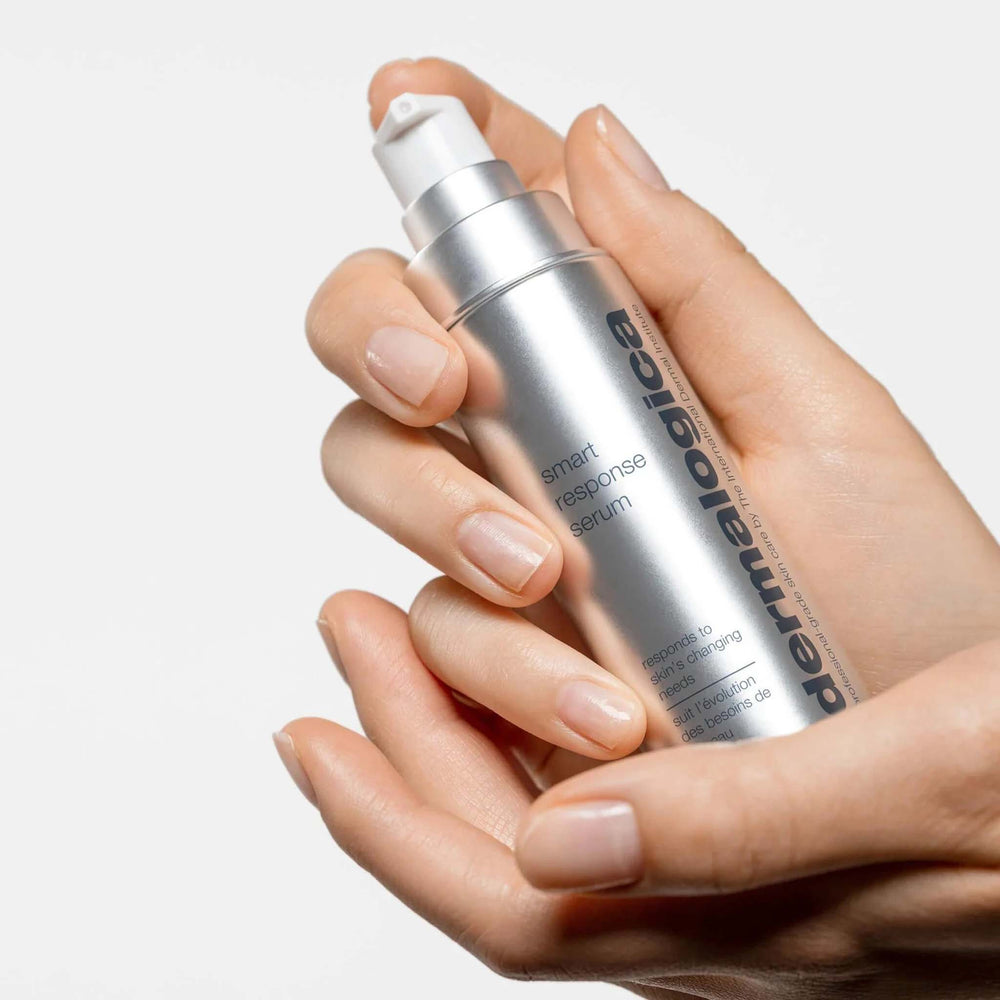 Hand holding a Dermalogica smart response serum bottle against a neutral background
